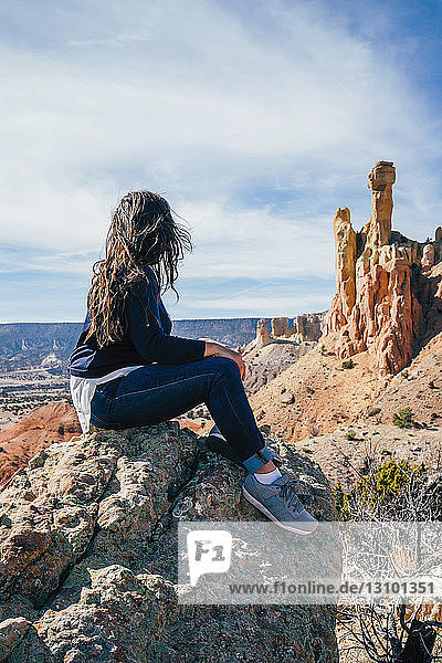 Frau betrachtet Aussicht  während sie auf einem Felsen in der Wüste sitzt