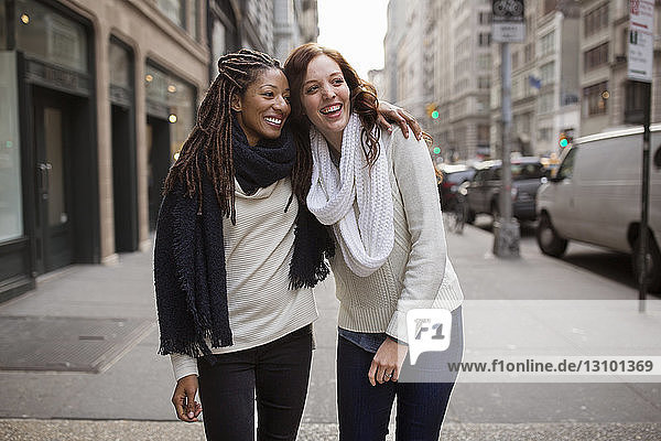 Smiling female friends enjoying on footpath