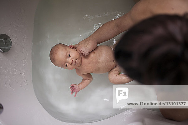 High angle view of mother bathing son in bathtub at home