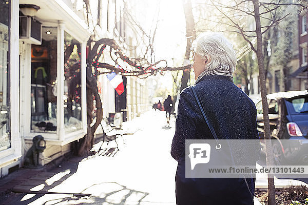 Rückansicht einer älteren Frau  die auf dem Bürgersteig geht