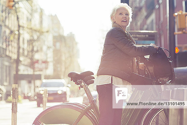 Ältere Frau schaut weg  während sie die Fahrradfreigabe vom Gepäckträger löst