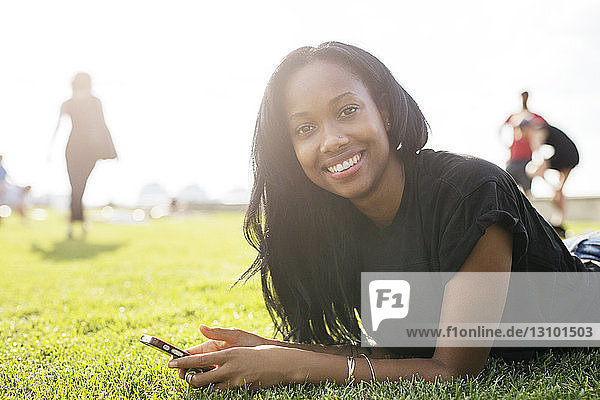 Portrait of happy woman lying on grassy field at park