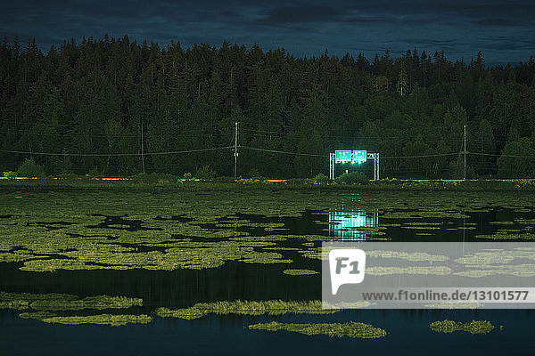 Beleuchtete Werbetafel am See während der Nacht