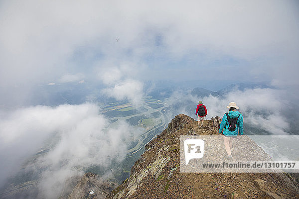 Hochwinkelaufnahme von Freunden beim Wandern auf einem Berg inmitten von Wolken
