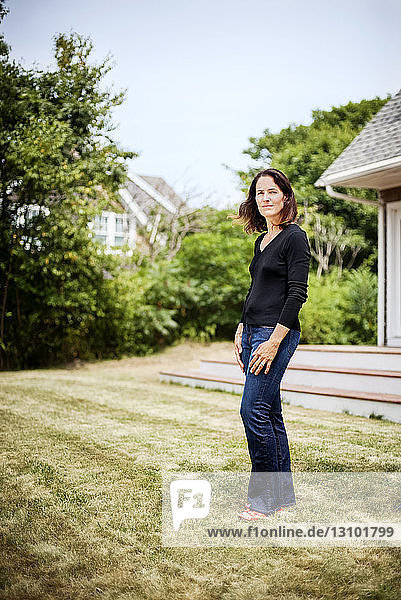 Portrait of woman standing in yard against sky