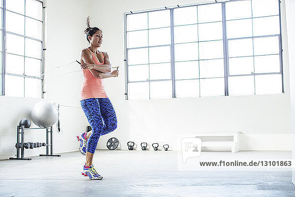 Female athlete exercising with jumping rope in gym