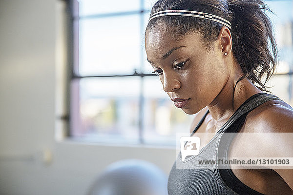 Close-up of female athlete looking down while standing in gym
