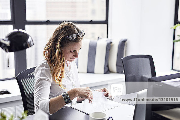 Schrägansicht einer Geschäftsfrau  die im Büro Dokumente studiert