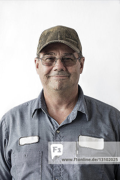 Portrait of manual worker wearing cap against white background