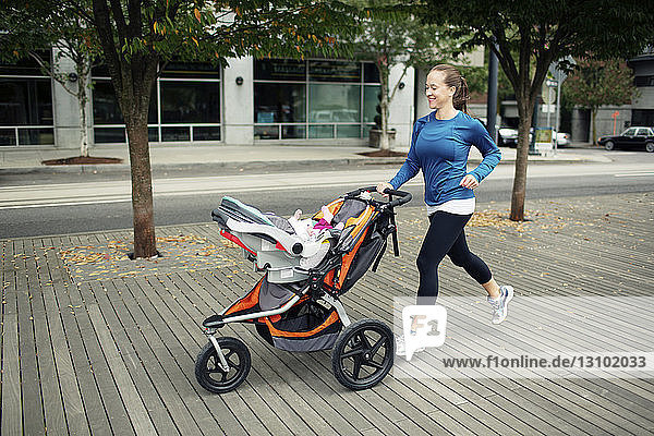 Cheerful woman looking at baby in while running on floorboard