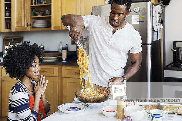 Man serving pasta to woman at dining table