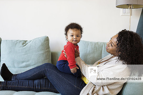 Mother looking at son while sitting on sofa
