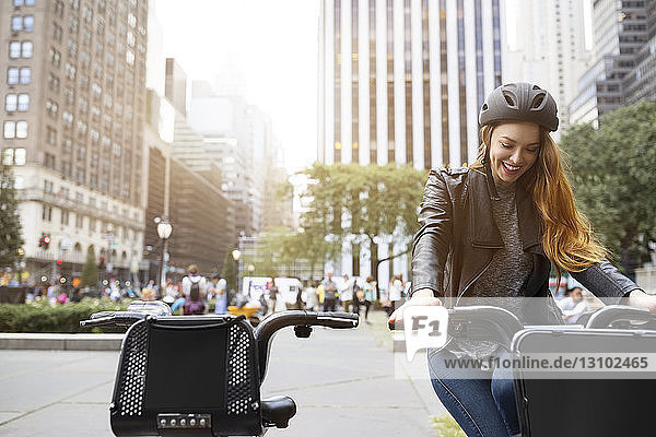 Happy woman sitting on bicycle at parking lot in city
