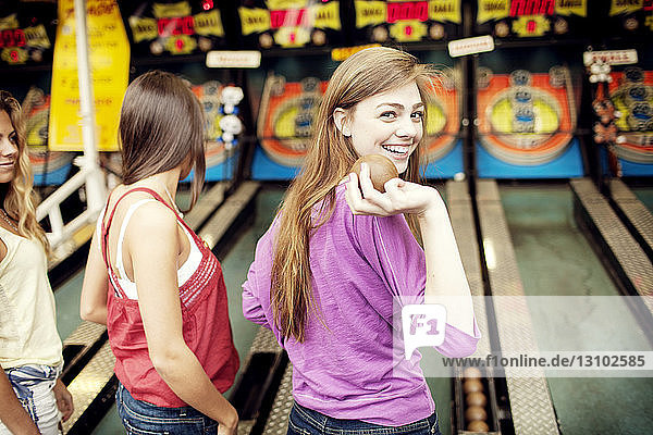 Porträt einer Frau  die den Ball hält  während sie bei Freunden am Jahrmarktstand steht