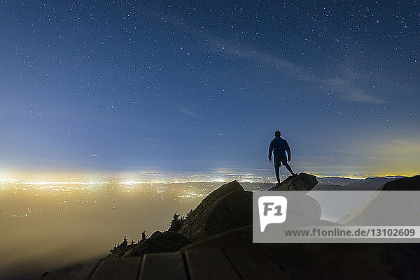 Silhouette man standing on rocks against star field at Mount Pilchuck State Park during night
