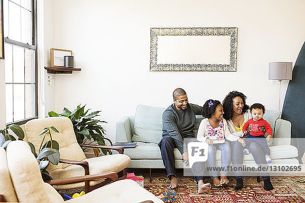 Glückliche Familie mit Bilderbuch  die den kleinen Jungen auf dem Sofa sitzend betrachtet