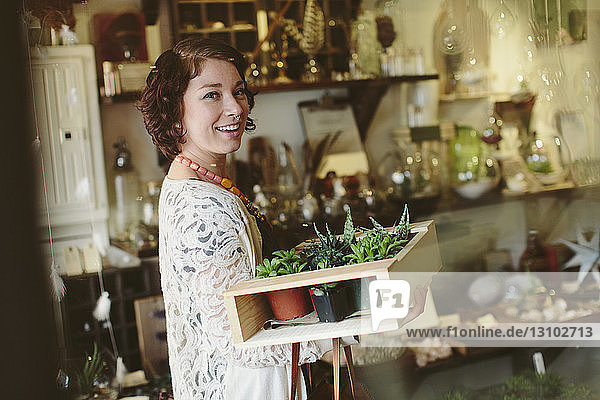 Porträt eines glücklichen Kunden  der Pflanzen in einer Kiste im Gartenzentrum trägt