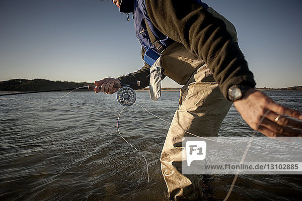 Ausgeschnittenes Bild eines Menschen  der auf See vor klarem Himmel fischt