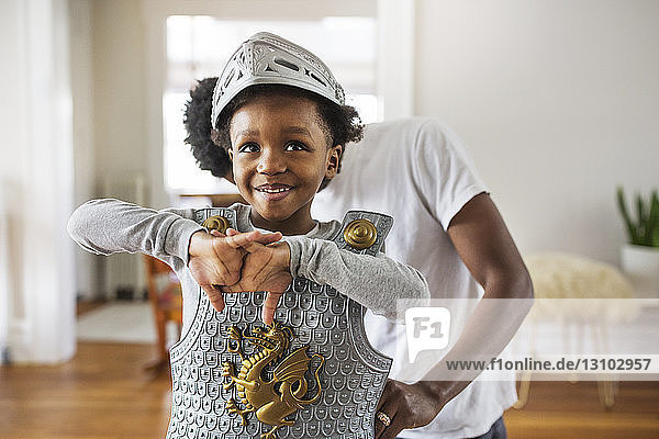 Father assisting cheerful boy in getting dressed as armor at home