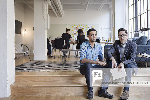 Porträt von seriösen Geschäftsleuten mit digitalem Tablet im Büro sitzend