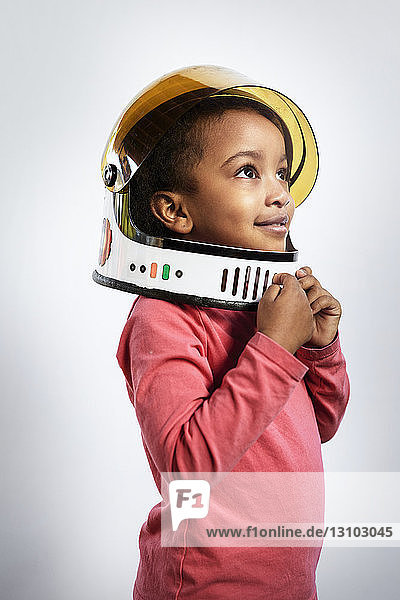 Nachdenkliches Mädchen mit Weltraumhelm beim Wegschauen vor weißem Hintergrund