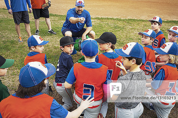 Baseball coach instructing boys on field
