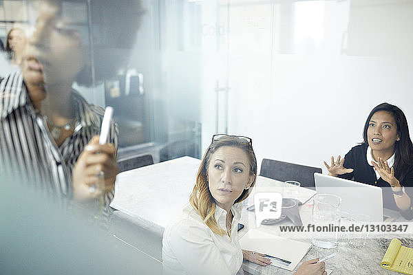 Female colleagues having discussion in office seen through window