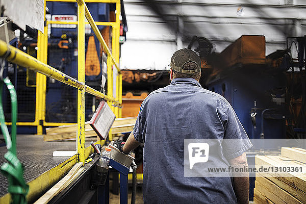 Rückansicht eines Arbeiters an einer Maschine in einer Fabrik der Metall-Stahlindustrie