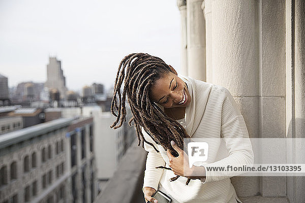 Happy woman playing with hair on balcony