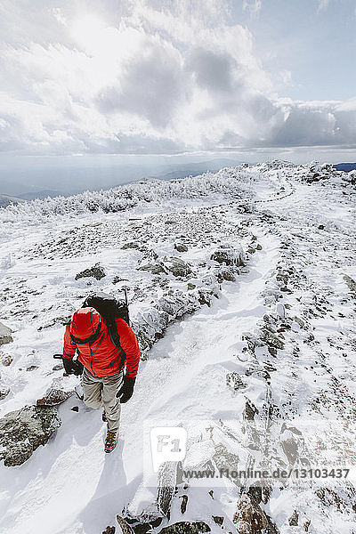 High angle view of backpacker wearing warm clothing walking on snow during winter