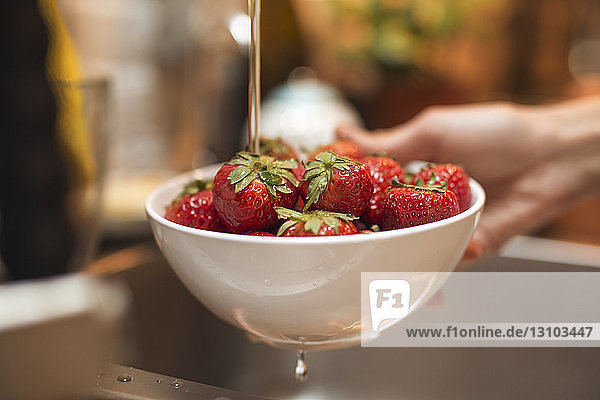 Ausgeschnittenes Bild einer Frau  die frische Erdbeeren in der Küche wäscht