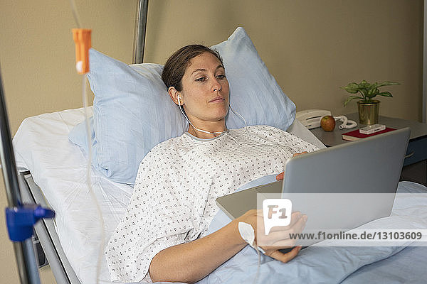 Weiblicher Patient  der einen Laptop benutzt und sich in einem Krankenhauszimmer ausruht und erholt
