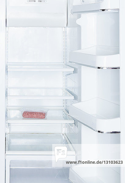 Ground beef in open  empty white refrigerator