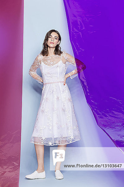 Young female fashion model wearing white dress and posing with colored panels