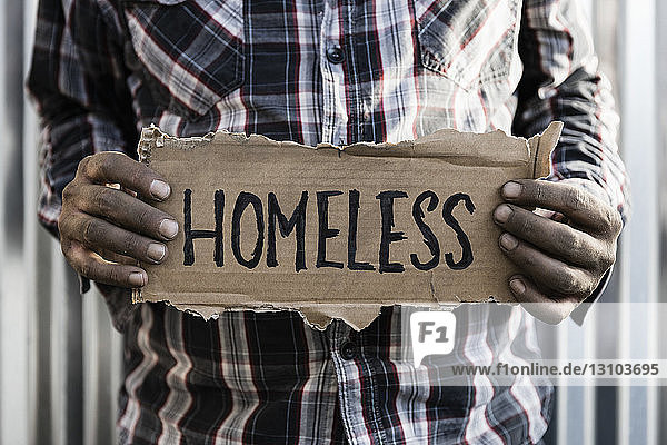 Obdachloser Mann hält Schild
