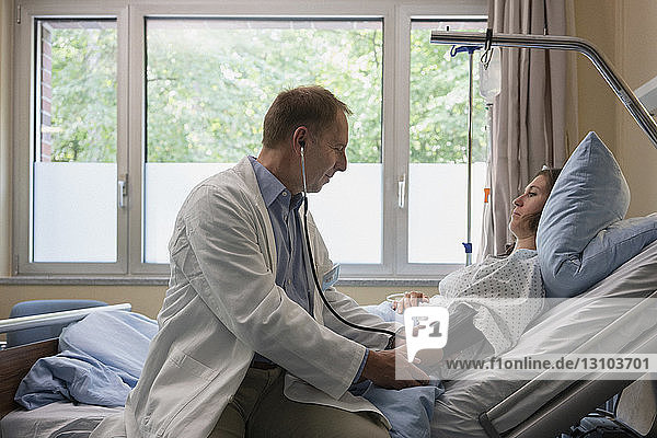 Arzt bei der Visite  Kontrolle des Blutdrucks eines Patienten im Krankenhauszimmer