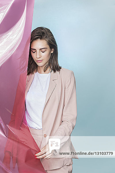 Portrait of a female fashion model posing with pink fabric and looking down