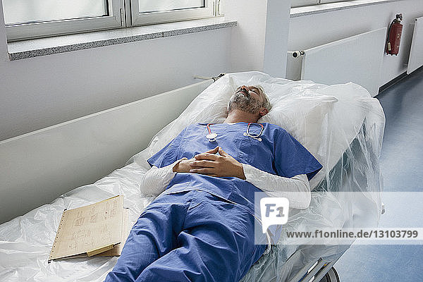 Erschöpfter Arzt ruht sich aus und schläft auf einer Bahre im Krankenhausflur