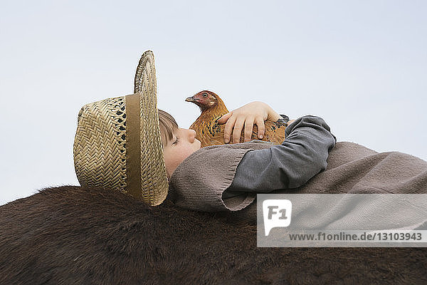 Girl hugging chicken  laying on horse