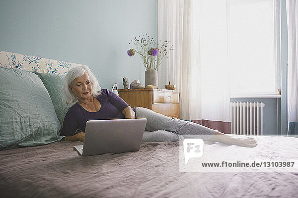 Senior woman using laptop on bed