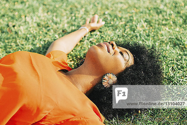 Sorglose  heitere junge Frau im sonnigen Gras liegend