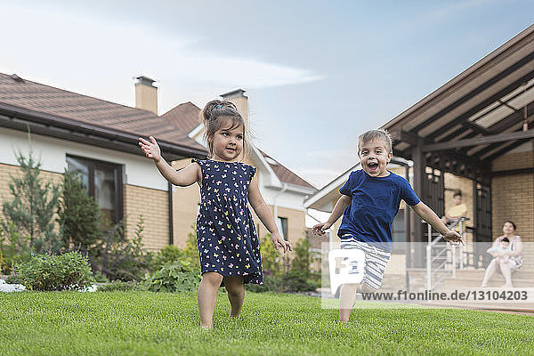 Brother and sister running  playing in backyard grass