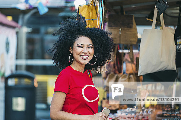 Porträt einer lächelnden  selbstbewussten jungen Frau beim Einkaufen an einem Marktstand