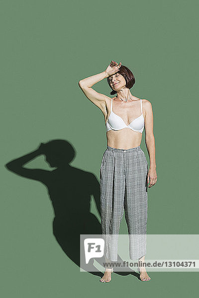 Portrait tired woman in bra against green background