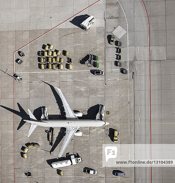 Blick von oben auf ein Verkehrsflugzeug  das auf dem Rollfeld eines Flughafens gewartet und vorbereitet wird