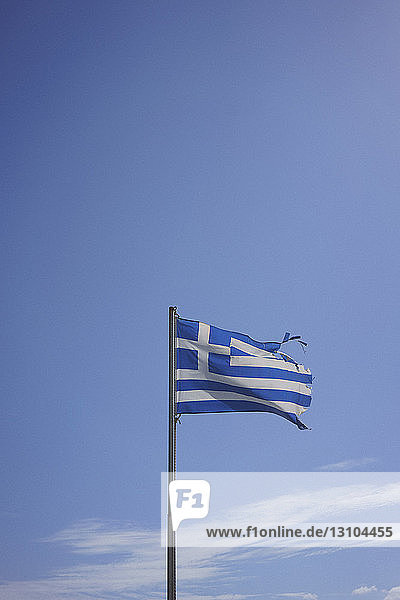 Zerrissene griechische Flagge weht im Wind gegen den sonnigen blauen Himmel