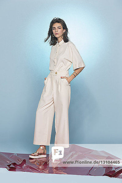 Portrait of female fashion model posing against blue background