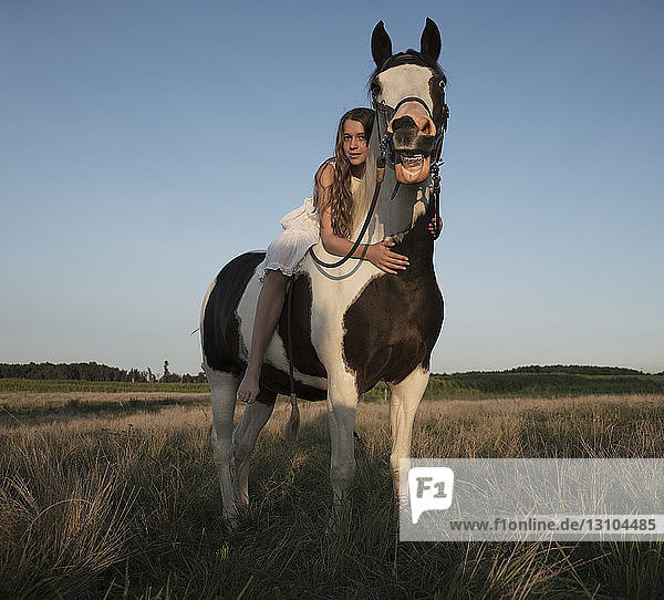 Portrait girl laying on horse in rural field