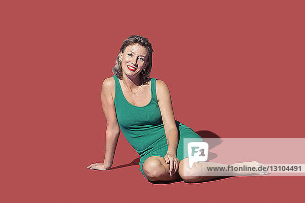 Portrait confident woman sitting on red background