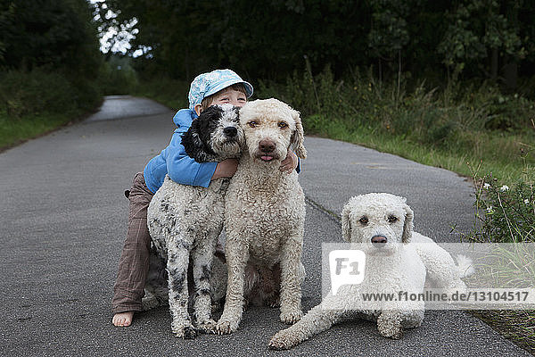 Portrait cute girl hugging dogs on rural road